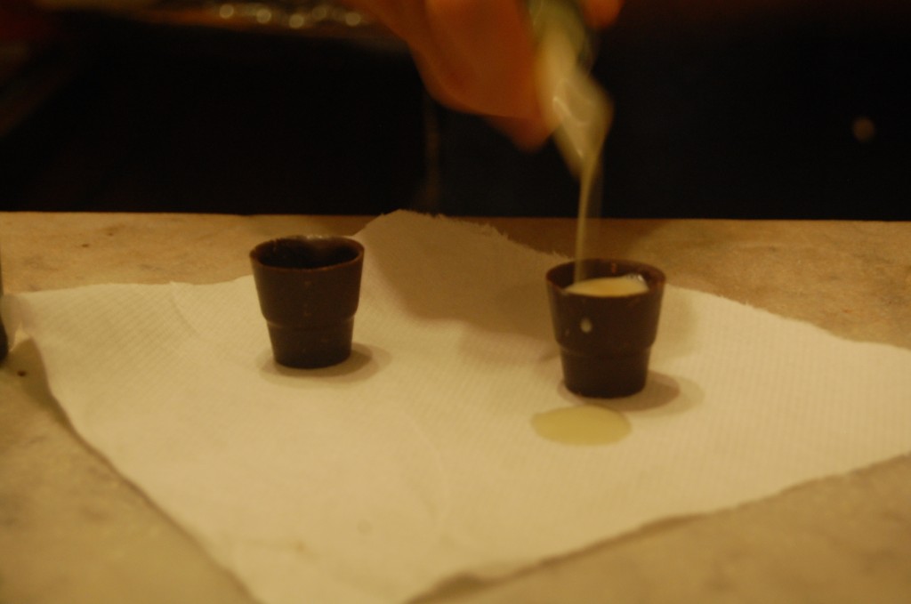 white drink being poured into chocolate shot glasses