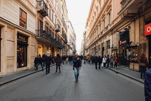 shopping in rome on via del corso where a man in sunglasses walks towards the camera in the middle of the street