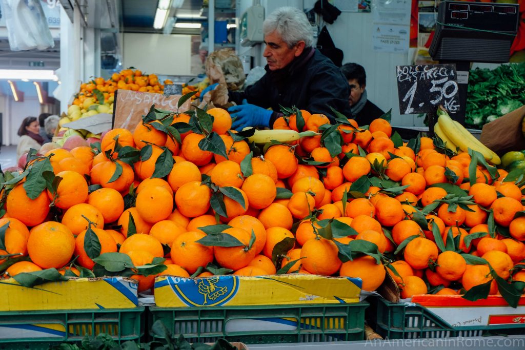 fresh oranges at Italian market with man working in background