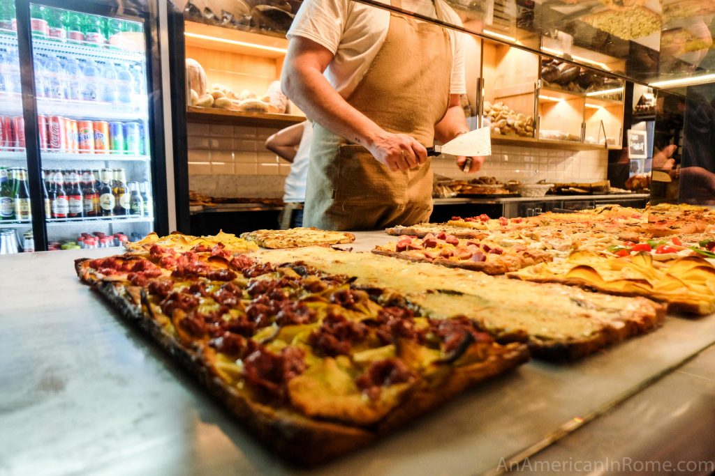 rows of pizza and hand ready to cut