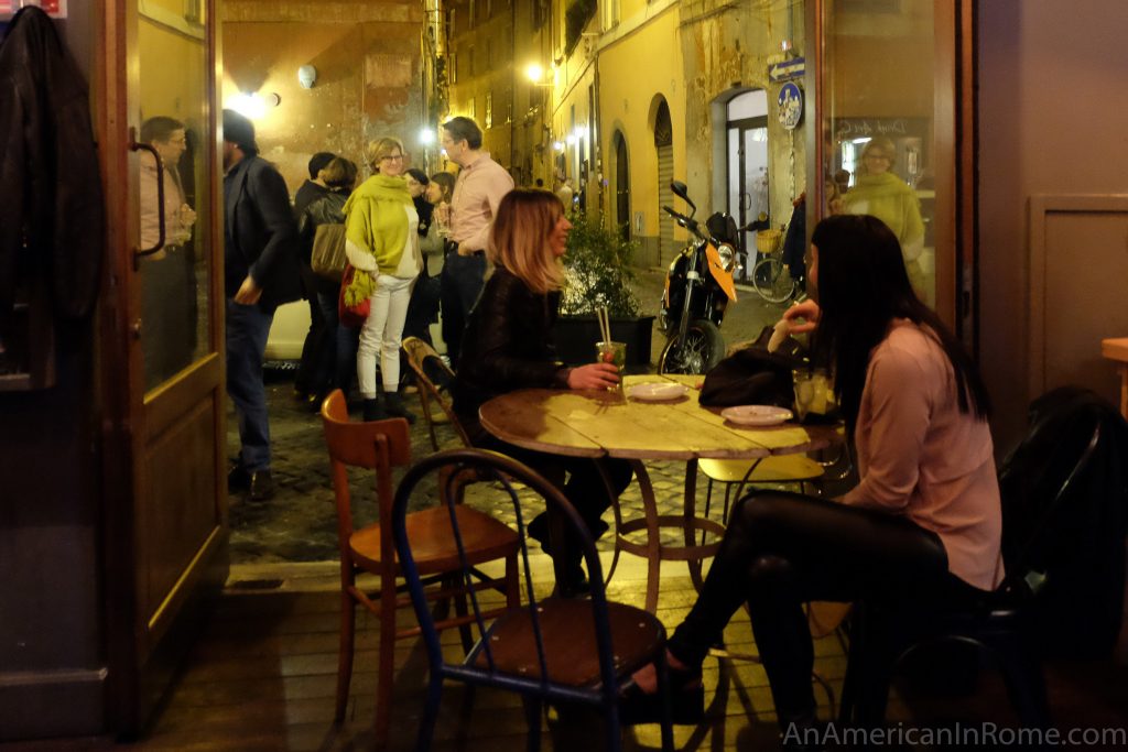 two girls sit at a table near an open door at Bar del Fico Rome