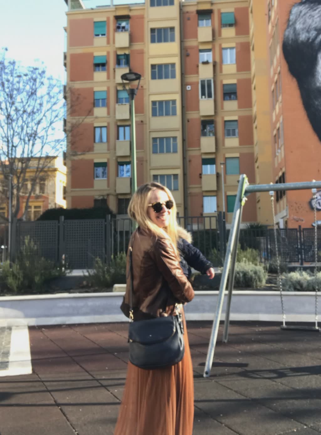 woman in a brown jacket and tan long skirt on playground