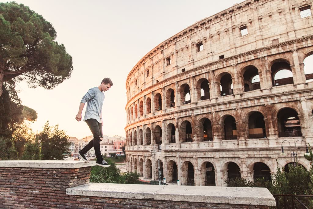 man walking on a wall with the colosseum close in the background