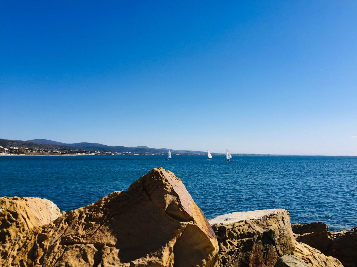 sailboats in the distance behind rocks