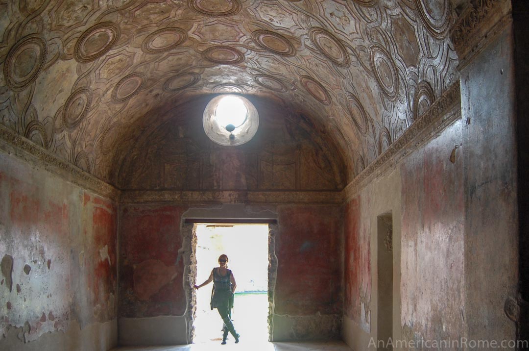 figure standing in a lit doorway at pompeii