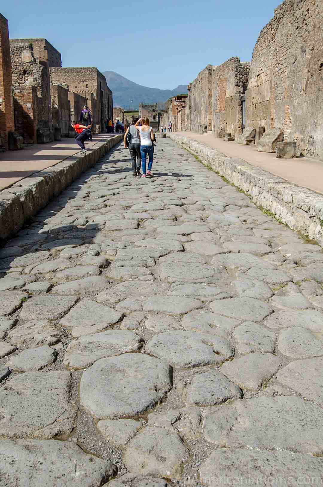 people walking on a stone road at Pompeii