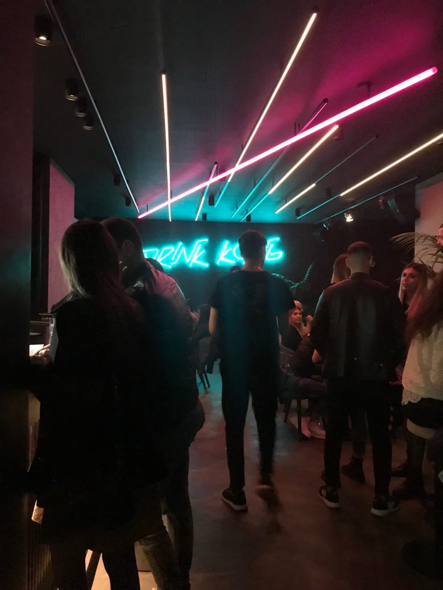 neon lights reading drink kong with people in the bar