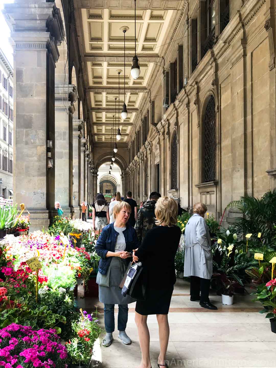 two women talk in a flower market