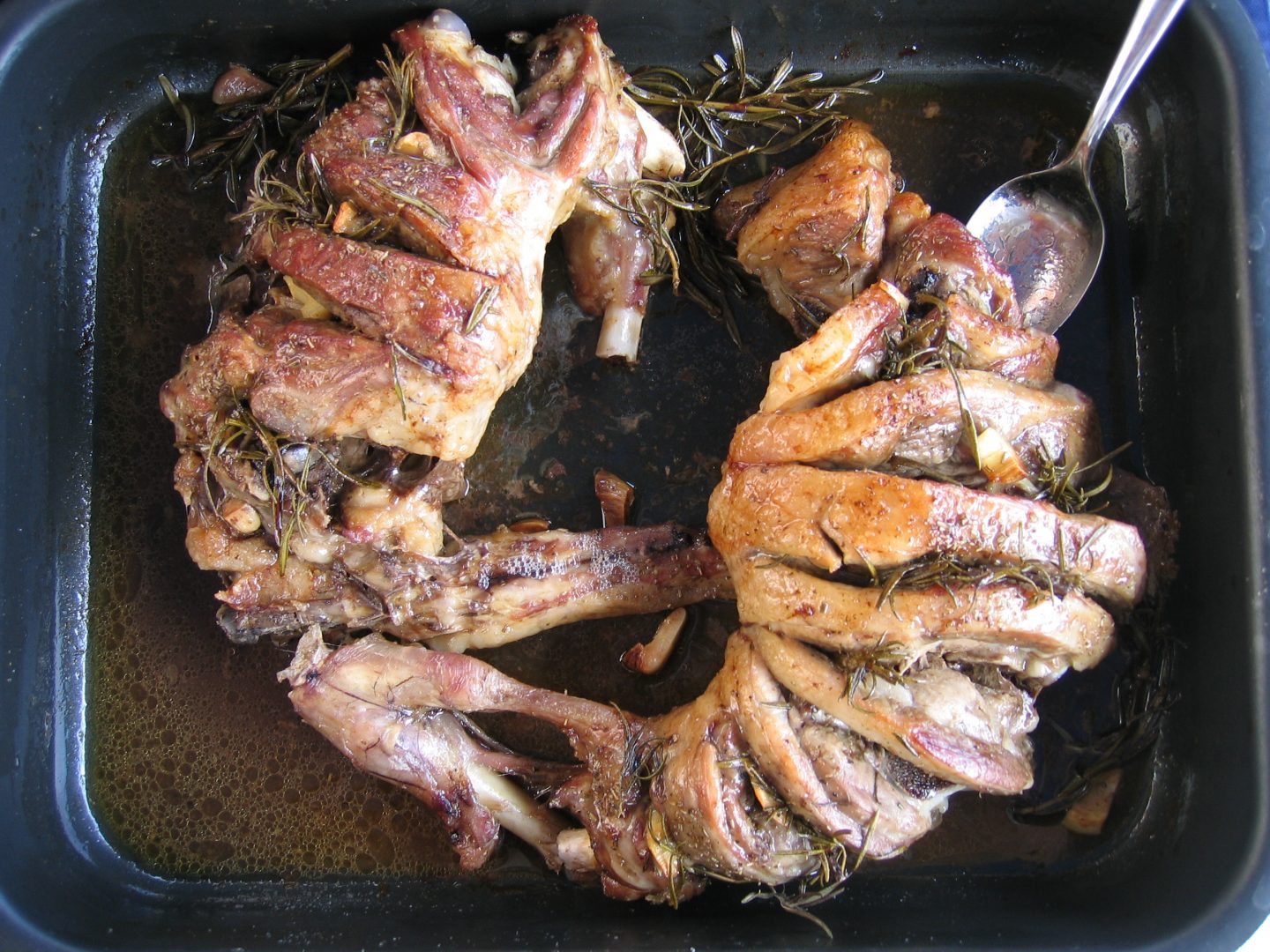 roast lamb with rosemary in black pan