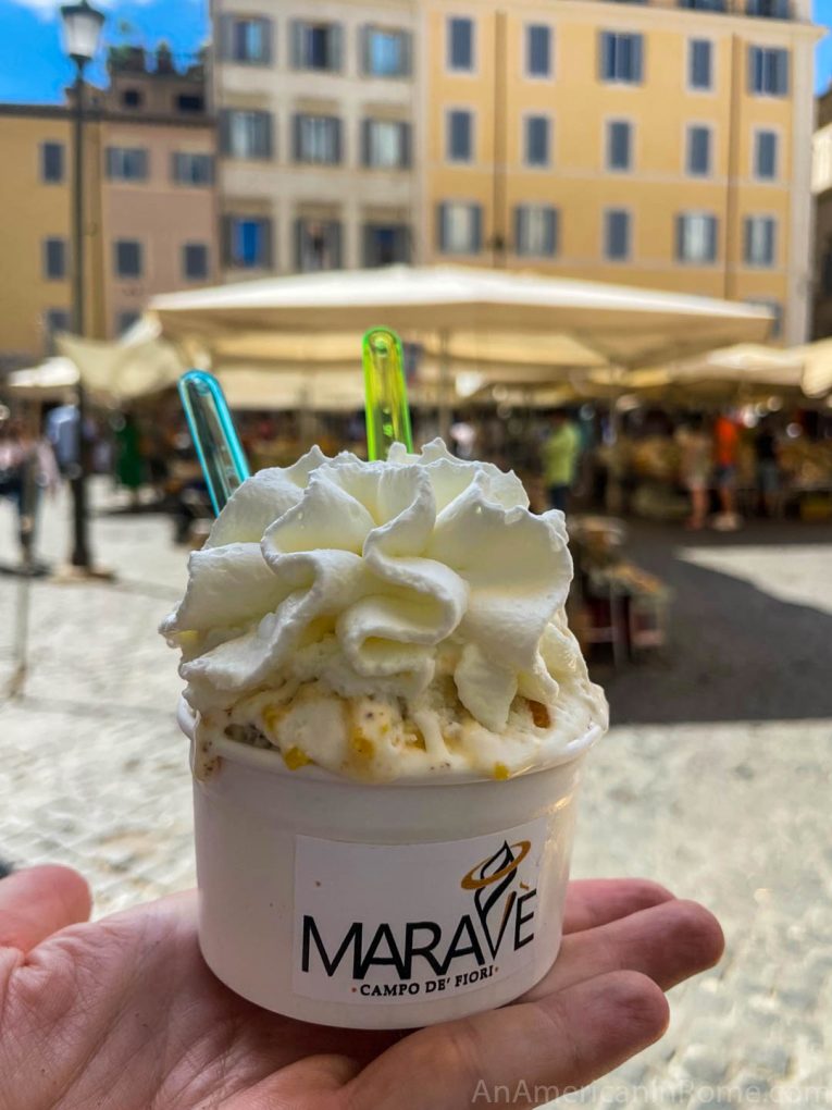 hand holding a cup of gelato with cream on top