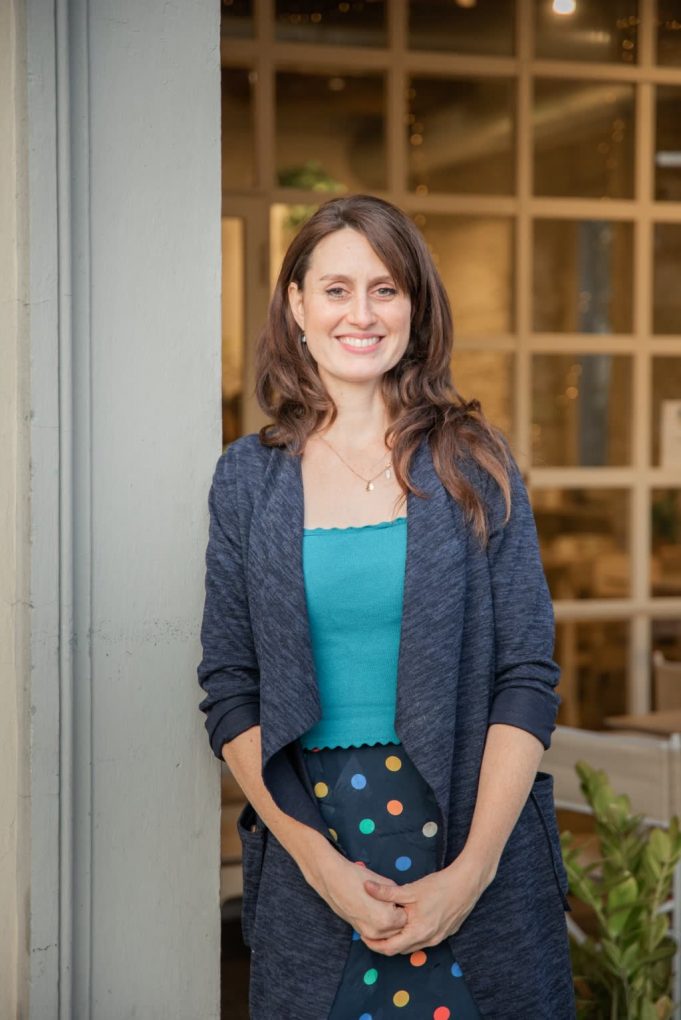 smiling woman with brown hair leaning on doorway