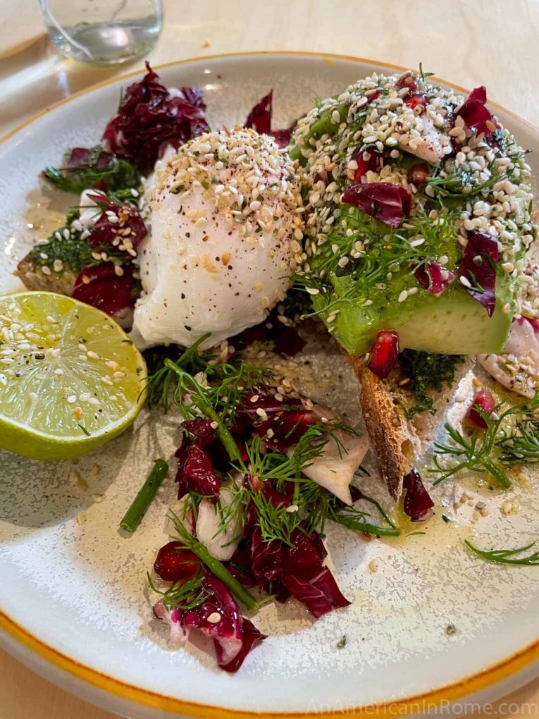 avocado toast with sesame seeds, a lime, and poached eggs